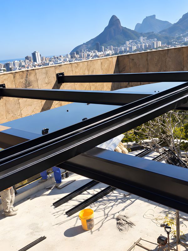 Estrutura de aço sendo montada na laje de um prédio no Rio de Janeiro, com o Morro Dois Irmãos ao fundo