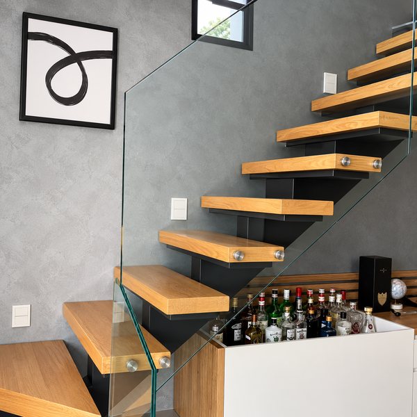 Degraus de madeira com guarda-corpo de vidro, em sala com quadro na parede
